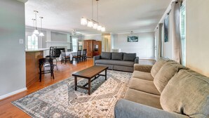A living room with a sofa, a coffee table, and a rug. There is a dining area with chairs and a table.