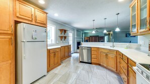 A kitchen with wooden cabinets, a white refrigerator, a dishwasher, and a white countertop.