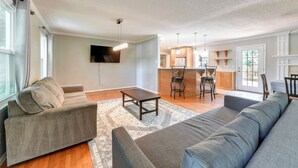 A modern living room with a sofa, a coffee table, and a TV mounted on the wall.