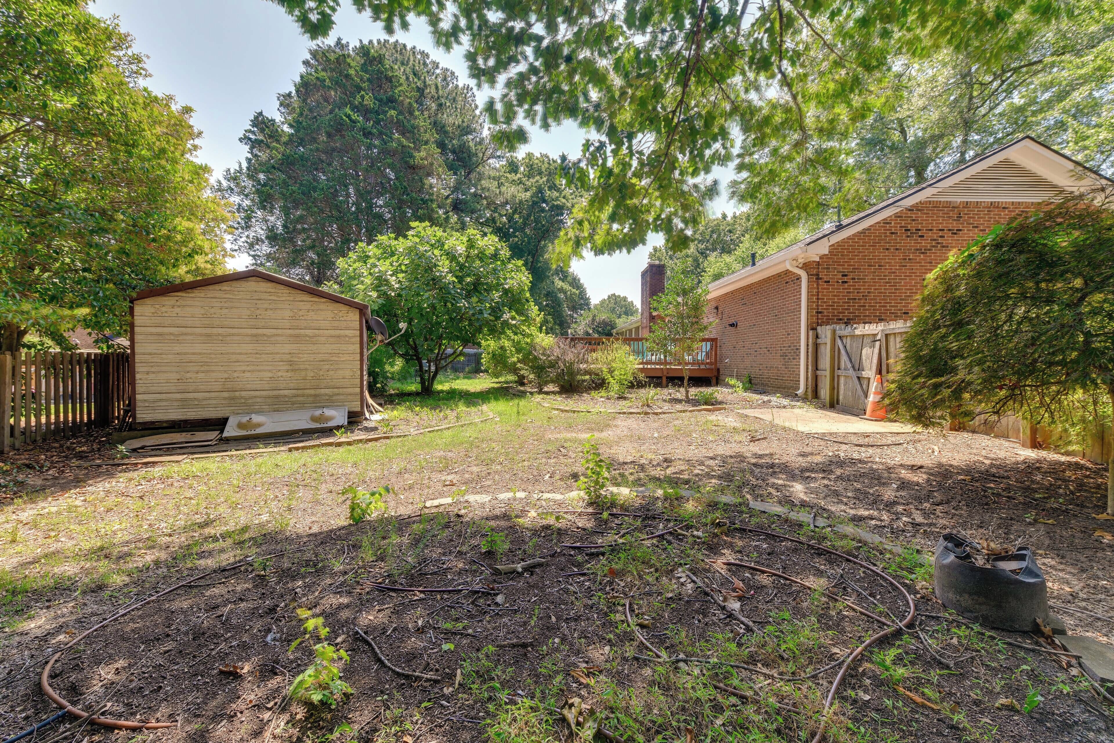 A backyard with a shed, a brick building, and a garden area.
