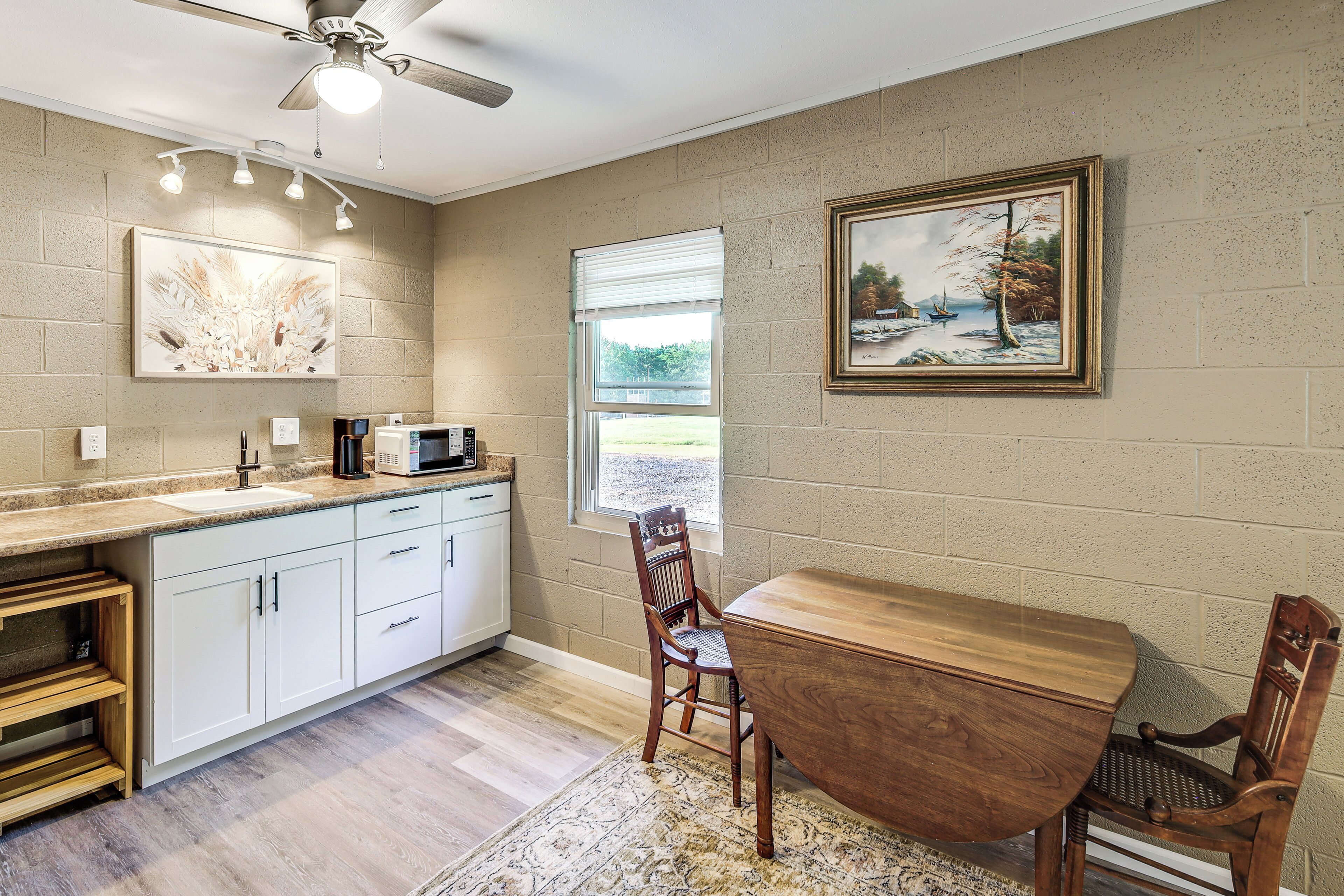 A kitchen with a dining area, a ceiling fan, a window, and artwork on the walls.