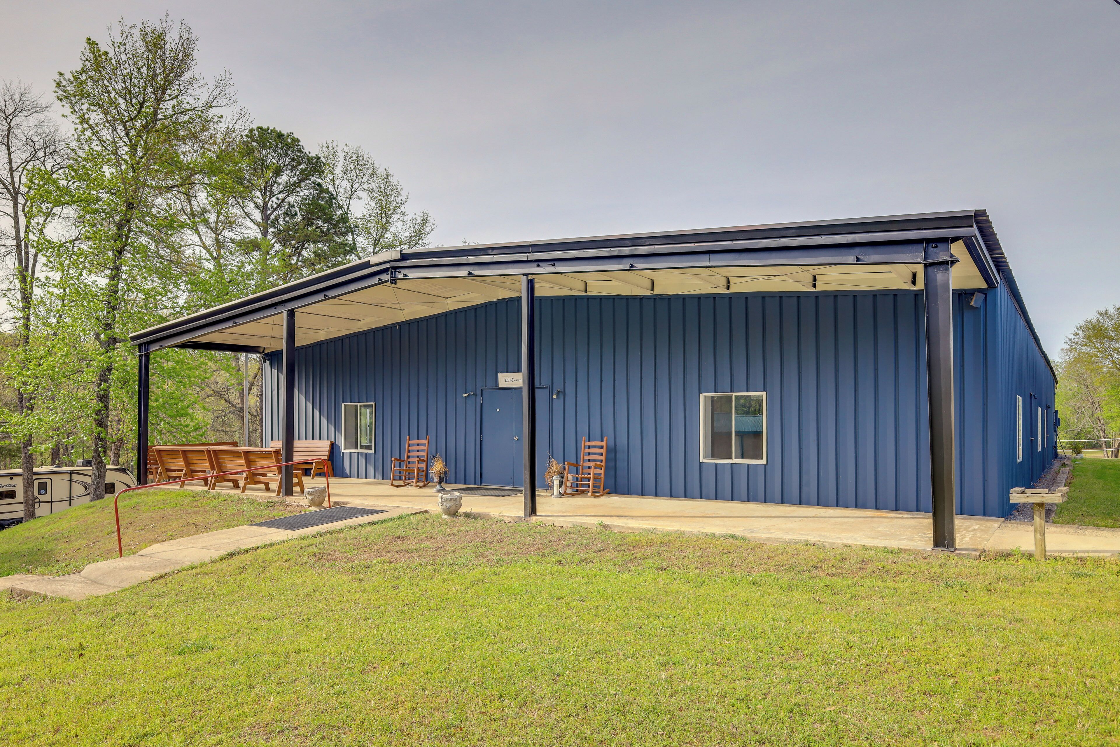 A blue building with a covered outdoor area, wooden benches, and chairs.