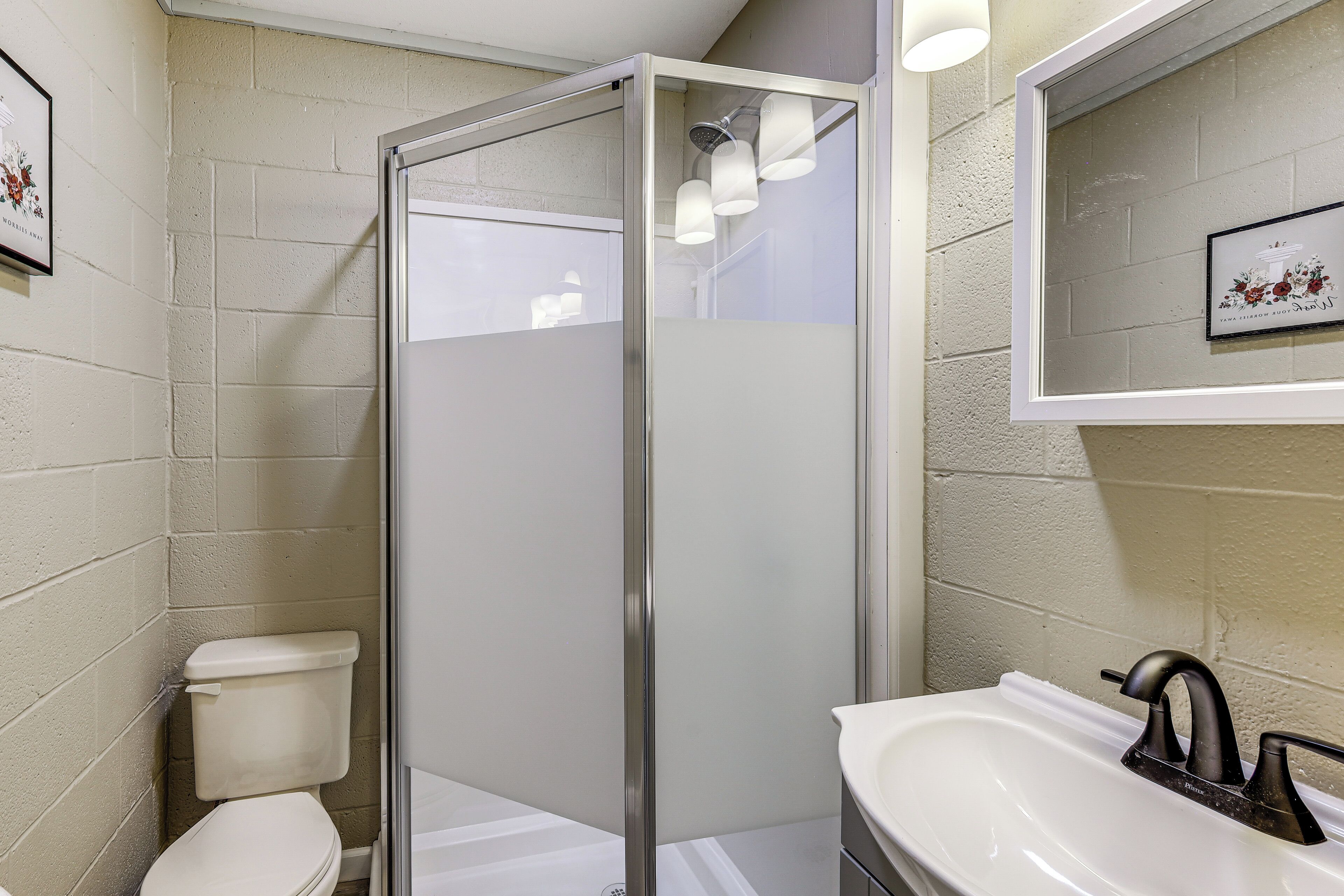 A bathroom with a glass-enclosed shower, a white toilet, and a sink with a black faucet.