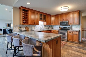 Una cocina con armarios de madera, encimera de granito, una vinoteca empotrada y un horno de acero inoxidable.