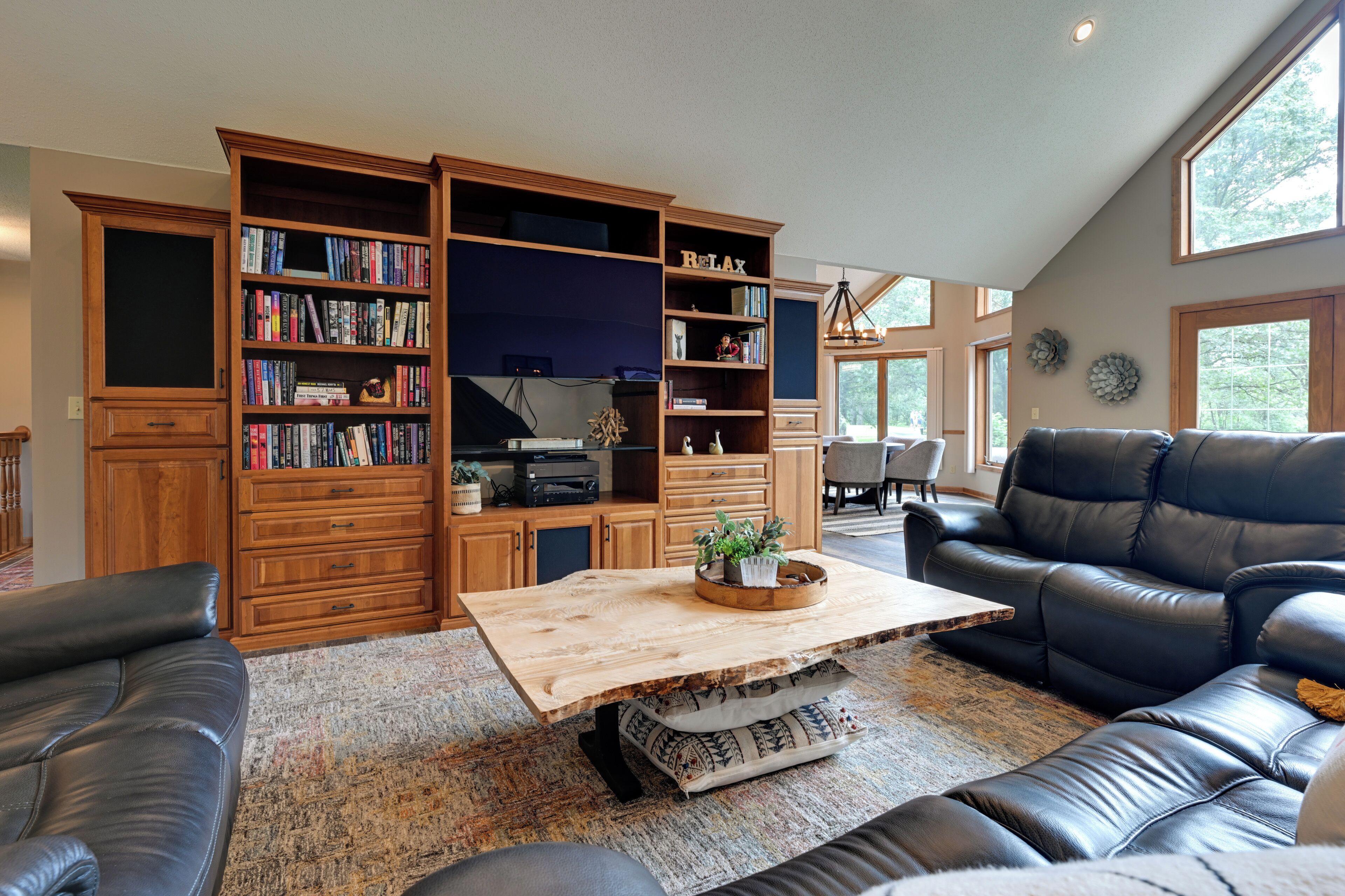 A spacious living room with a large wooden bookshelf, leather sofas, and a coffee table.