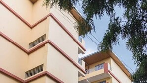 Un immeuble à plusieurs étages, doté d’une façade sobre, de balcons et d’une entrée fermée par un portail.