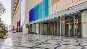 Un bâtiment moderne doté d’une façade en verre, d’un hall d’entrée carrelé et d’une enseigne indiquant « BURJUMAL ».