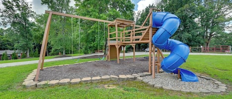 A playground with a wooden swing set and a blue spiral slide.