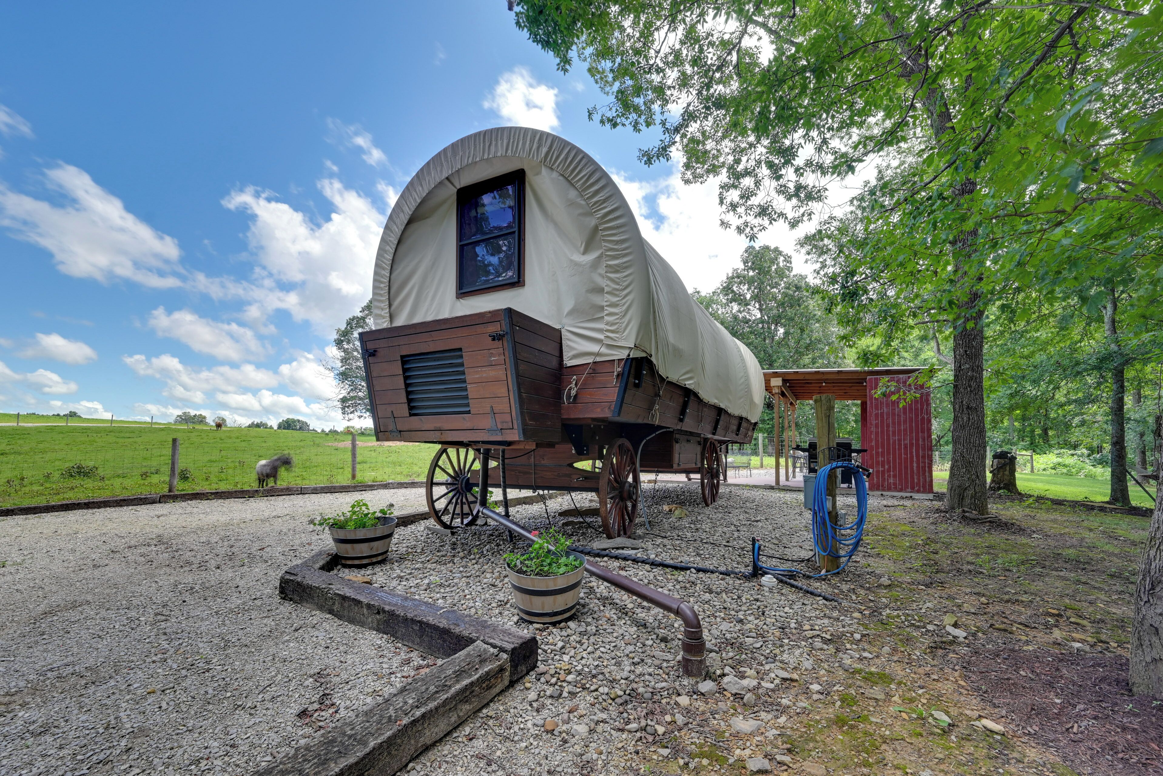 A covered wagon with a curved roof, wooden wheels, and a small window.