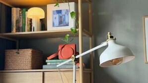 A room with a wooden bookshelf, a floor lamp, and a cushion. - Stylish 3-Bed Retreat Near the Peak District | Modern Comfort & Boutique Style (Burton-on-Trent)