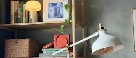 A room with a wooden bookshelf, a floor lamp, and a cushion.