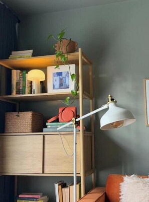 Ein Zimmer mit einem Holzbücherregal, einer Stehlampe und einem Kissen.