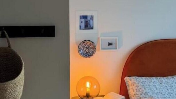 A bedroom with a bed, bedside table, lamp, and wall-mounted decor. - Stylish 3-Bed Retreat Near the Peak District | Modern Comfort & Boutique Style (Burton-on-Trent)