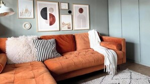 A modern living room with a sofa, framed artwork, and a lamp. - Stylish 3-Bed Retreat Near the Peak District | Modern Comfort & Boutique Style (Burton-on-Trent)