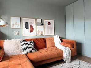 Ein modernes Wohnzimmer mit einer Couch, gerahmten Kunstwerken und einer Lampe.