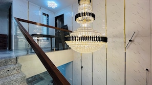 A staircase with a wooden handrail, a chandelier, and a wall with a marble pattern.