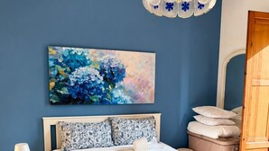 Ein Schlafzimmer mit einem großen Bett, einer Nachttischlampe, einem Gemälde und einer Holztür.