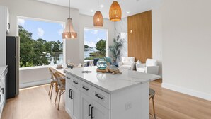 Una cucina moderna con una grande isola, luci a sospensione e vista sull'acqua.