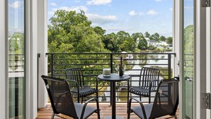 Un balcone con tavolo e sedie, vista su un lago e alberi.