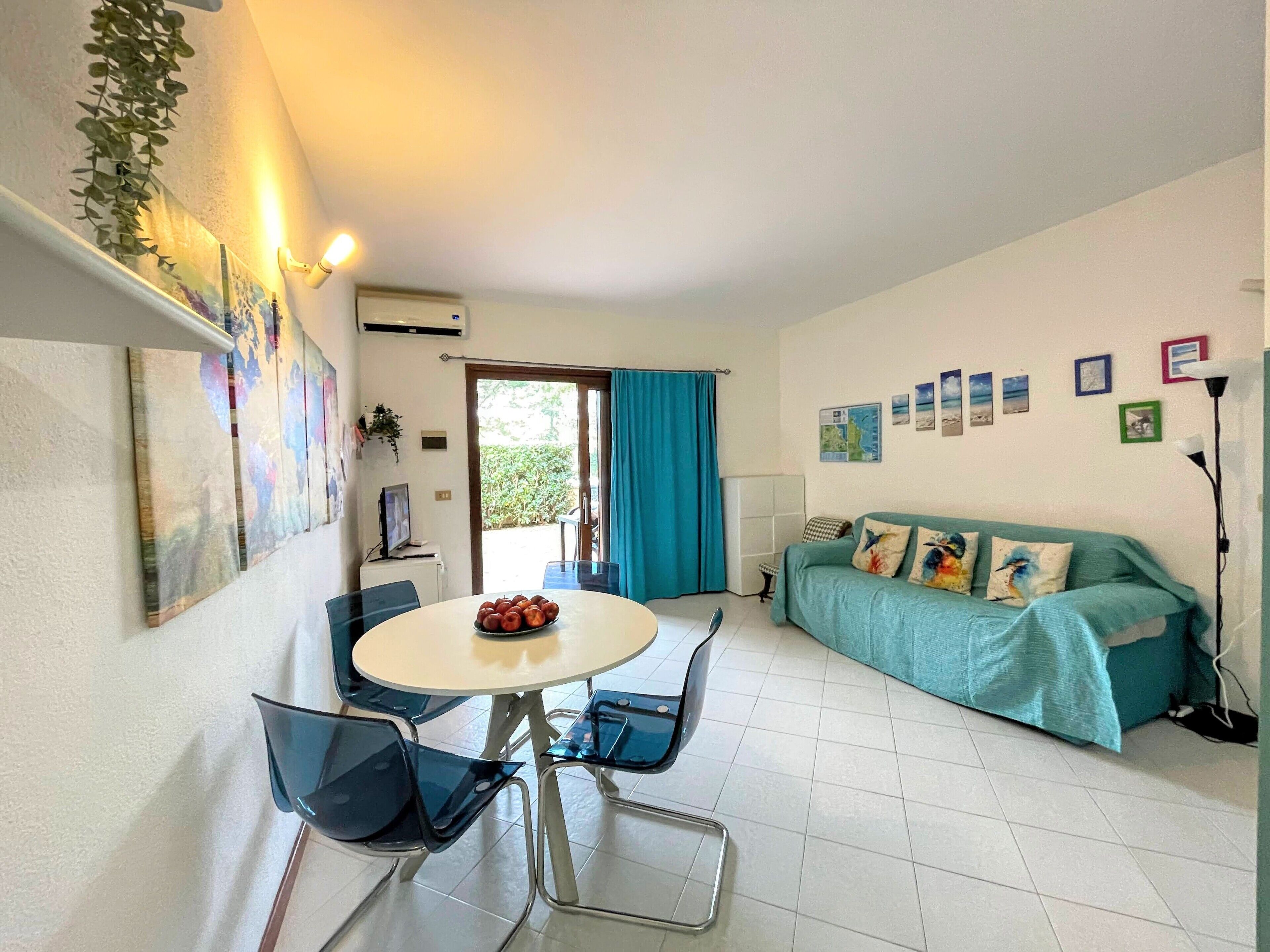 Een kamer met een eettafel, stoelen, een bank en een televisie.