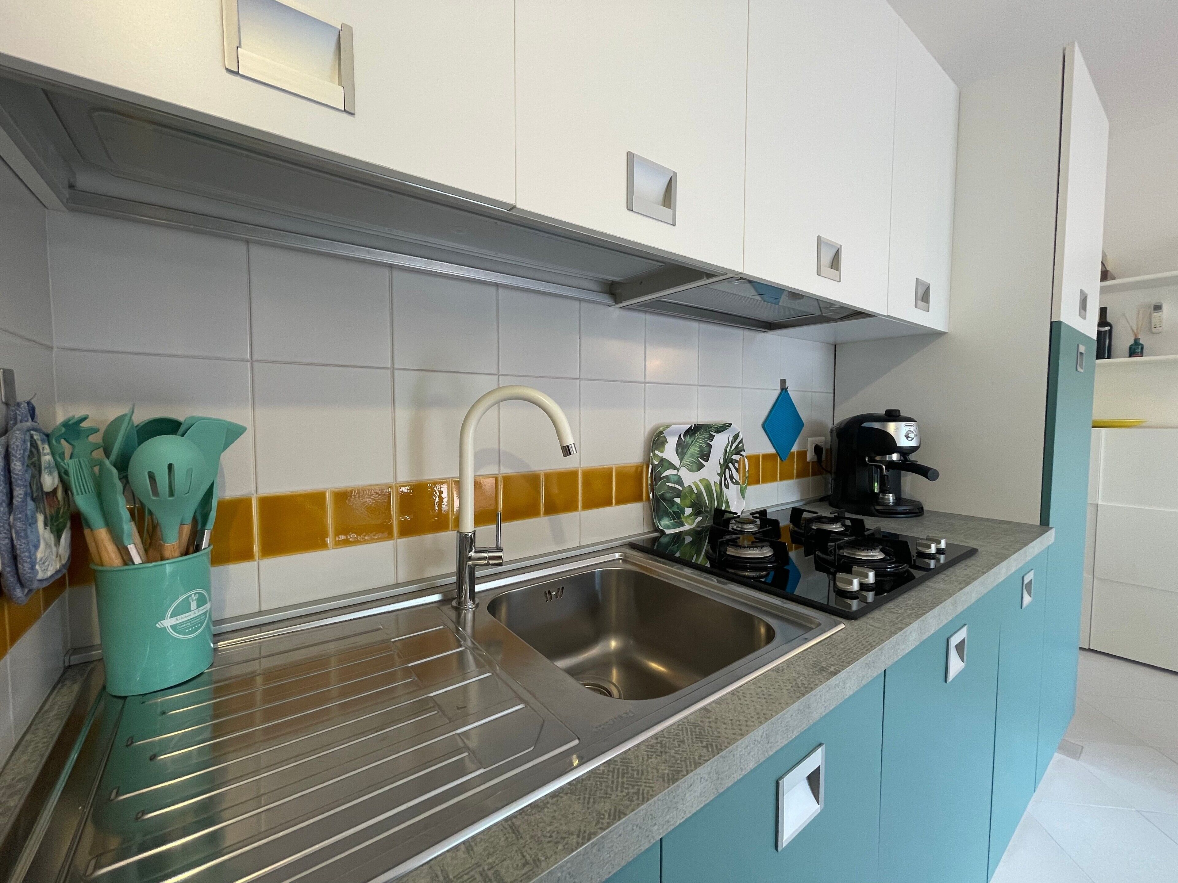A kitchen with a stainless steel sink, a gas stove, and a coffee maker.