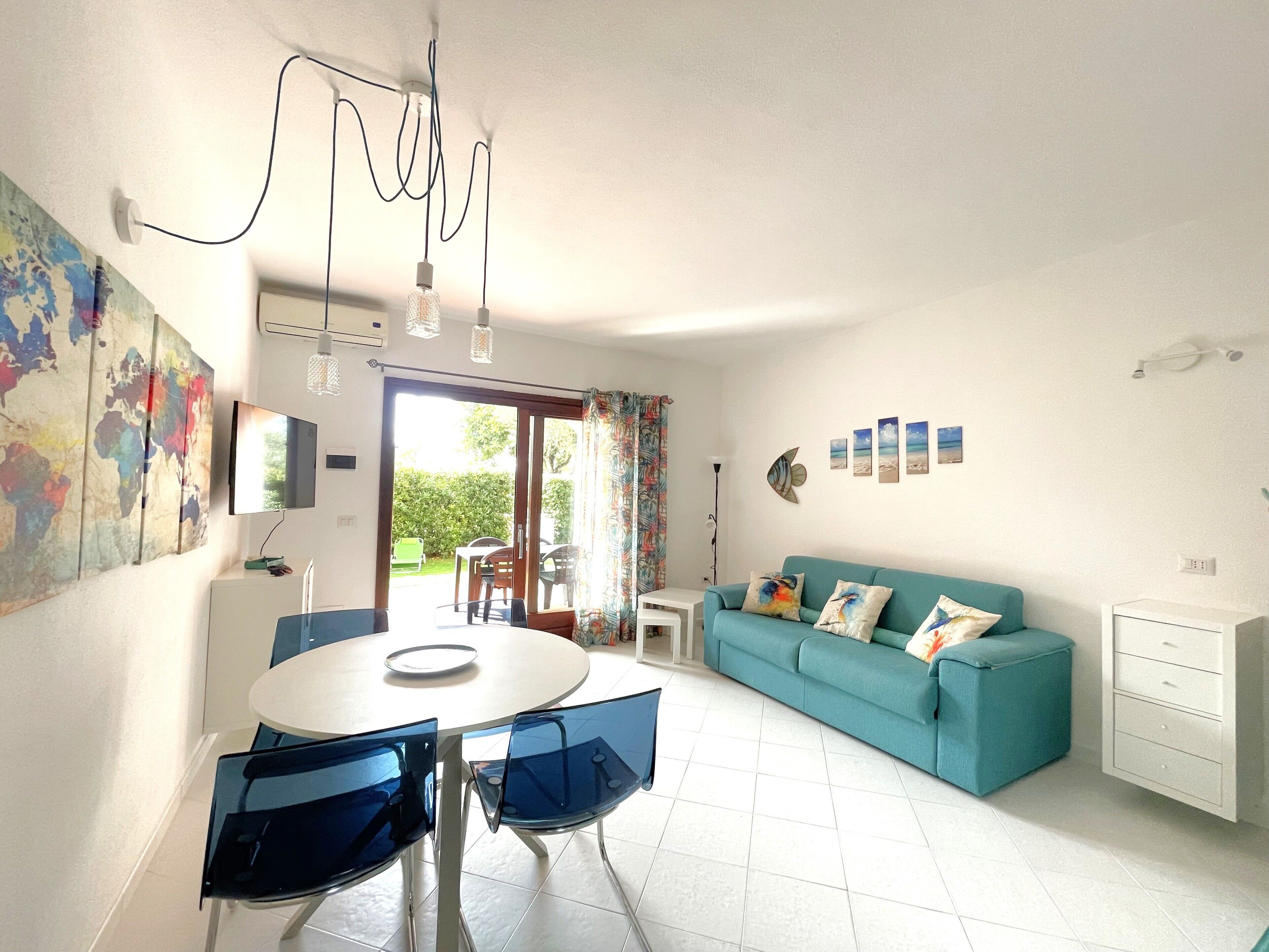 A modern living room with a round glass table, a teal sofa, and a large world map on the wall.