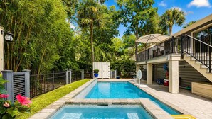 Ein Swimmingpool mit Basketballkorb, umgeben von einem Zaun und Grünpflanzen.