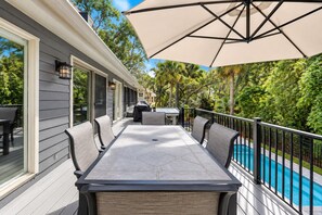 A covered outdoor patio with a dining table and chairs, a barbecue grill, and a swimming pool. - 28 Ruddy Turnstone - Coastal Retreat Near the Beach with Private Pool (Hilton Head Island)