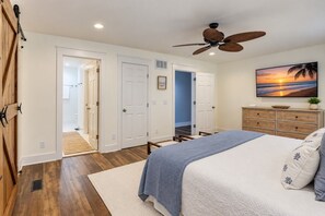 Une chambre avec un lit, un ventilateur de plafond, une télévision et une vue sur le coucher de soleil.