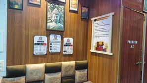 Habitación de hotel con pared de madera, un sofá con cojines, cuadros enmarcados y un cartel con información.