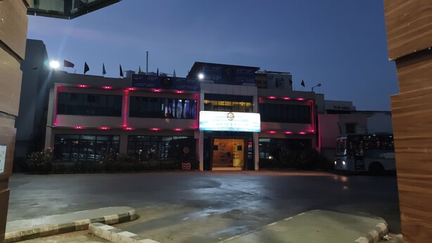 Un edificio con un letrero que dice 'MCCOMMUNITY HOTEL' y un estacionamiento enfrente.