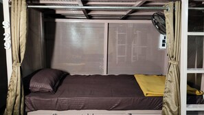 A bunk bed with a headboard, a pillow, and a blanket. - Suvidha Dormitory Hotel (Bhuj)