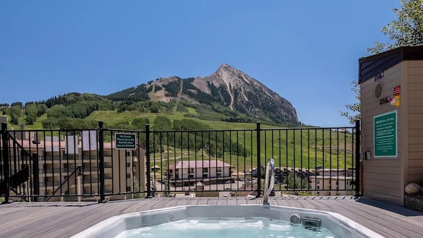 Een hottub met een houten terras, een berg op de achtergrond en een poort met een bordje.