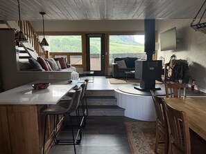 Eine moderne Küche mit Barbereich, Essbereich und einer Sitzecke mit Blick ins Freie.