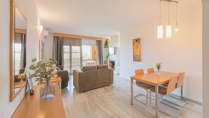 Una sala moderna con sofá, mesa de comedor, sillas, chimenea y un espejo grande.