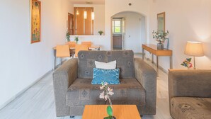 Una sala de estar con sofá, una mesa de centro, un comedor con mesa y sillas, y una zona de cocina.