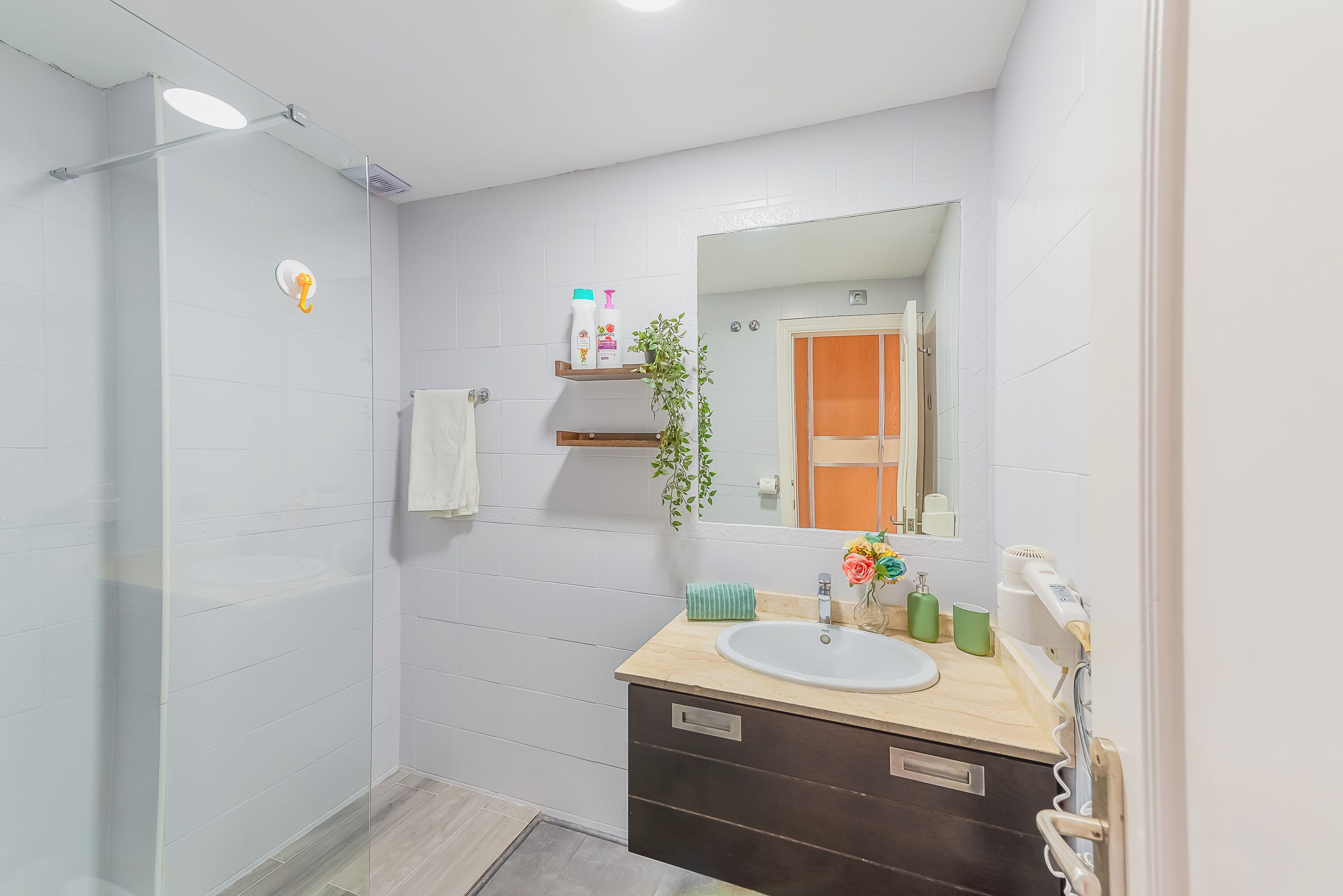 A modern bathroom with a glass shower enclosure, a sink with a mirror above it, and a towel rack.