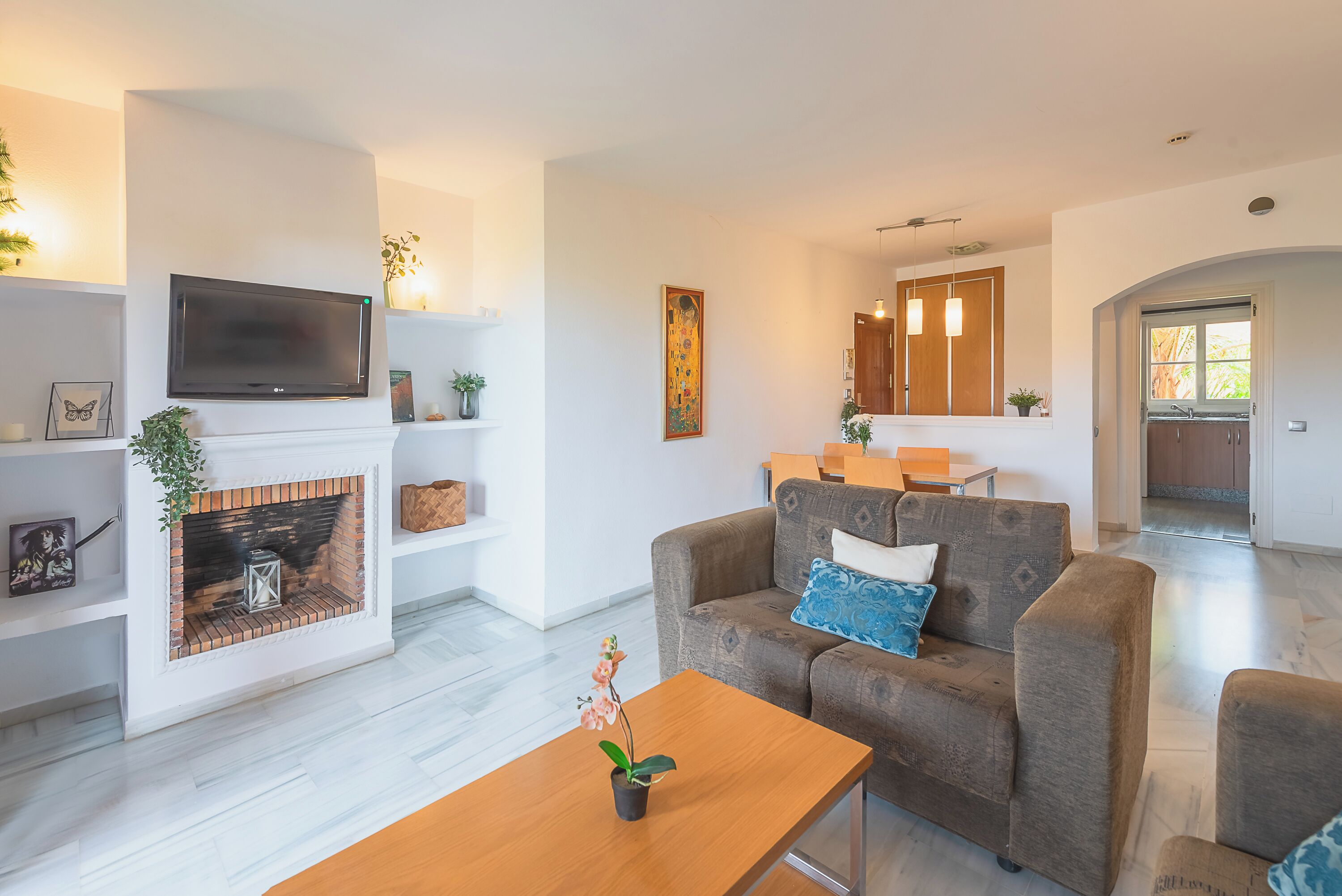 Una sala de estar moderna con chimenea, un televisor de pantalla plana, un sofá con cojines y una mesa de centro.