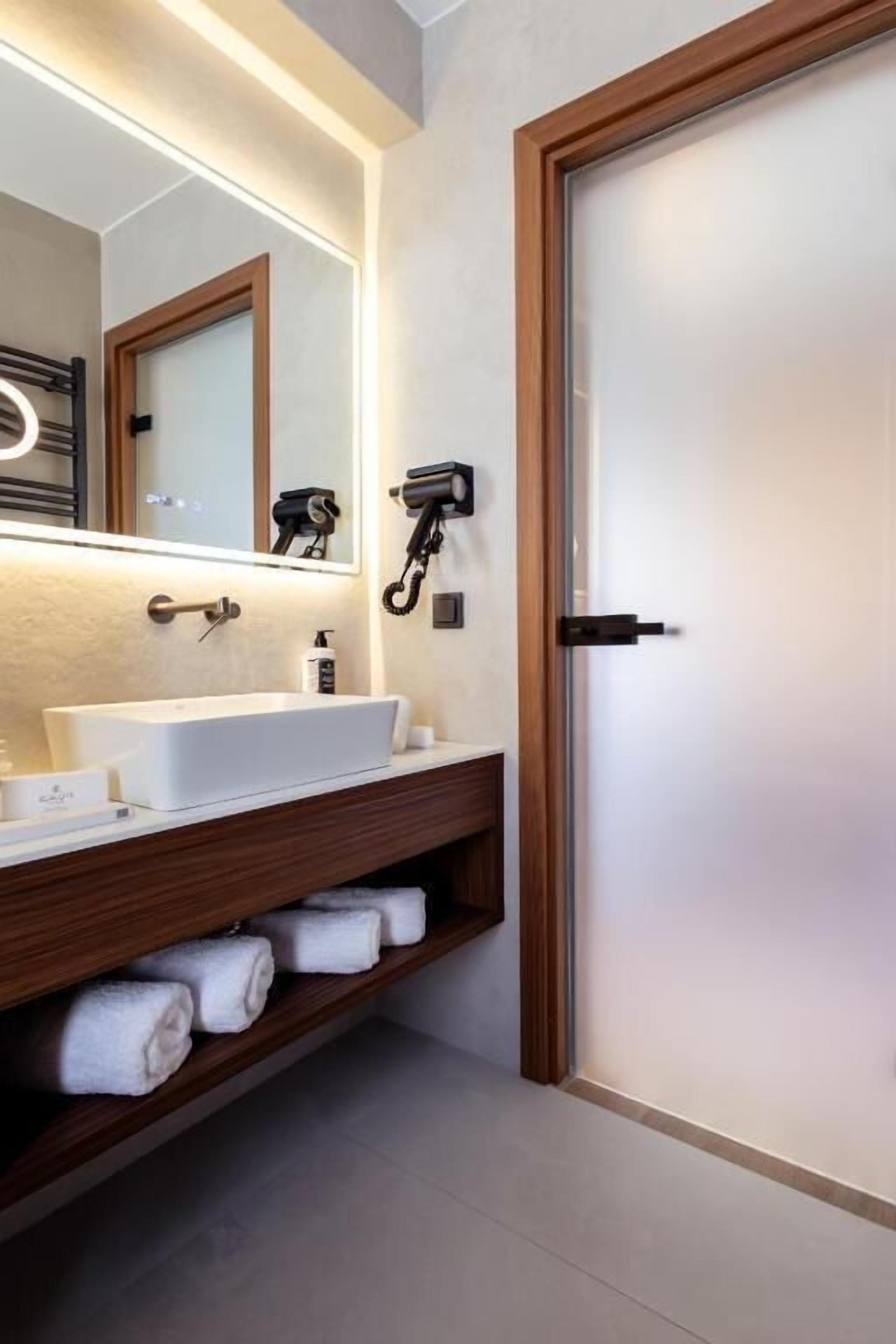 A bathroom with a wooden vanity, a large mirror, a hairdryer, and a towel rack.