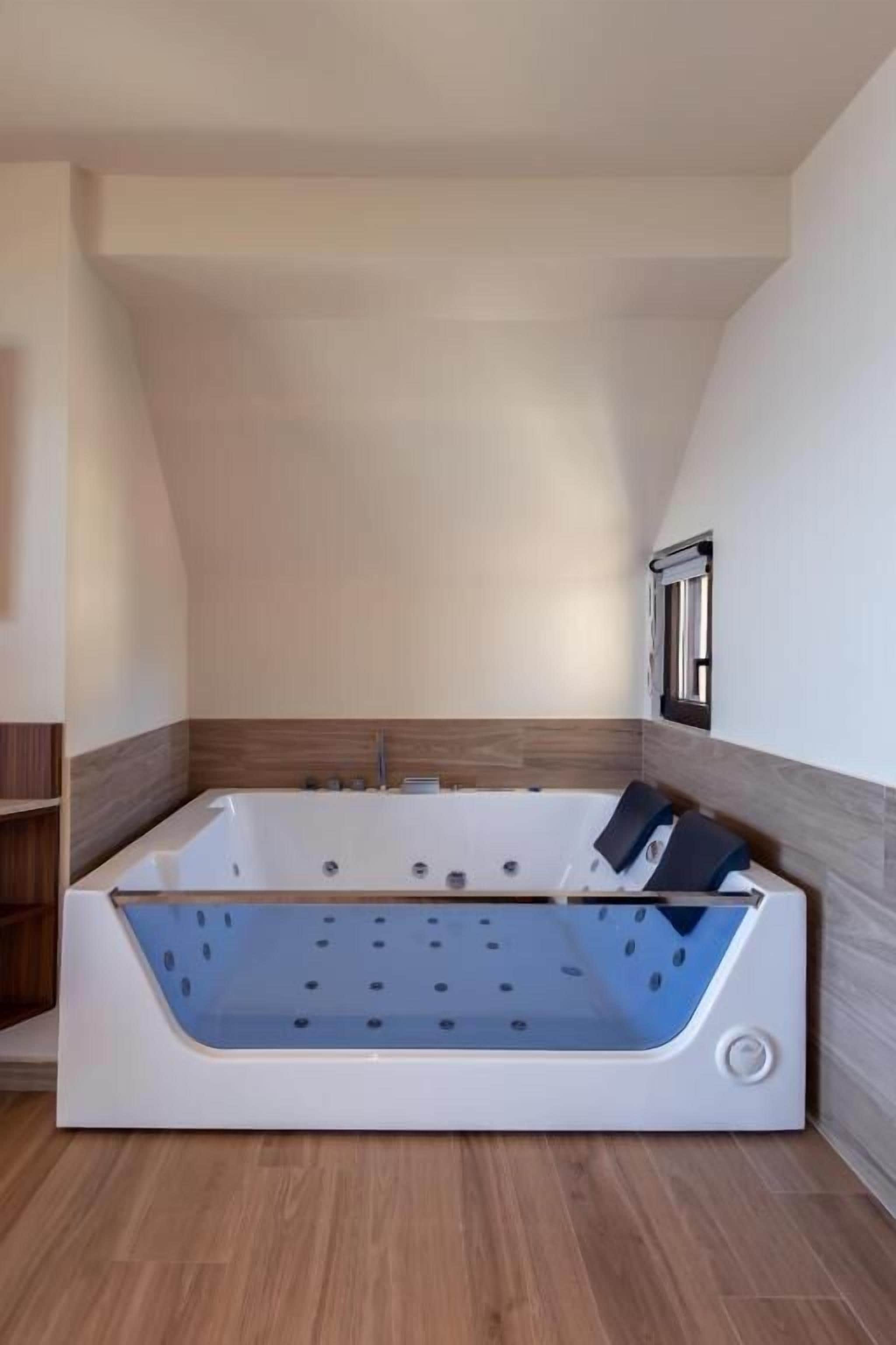 A modern bathroom with a freestanding bathtub, wooden flooring, and a built-in shower.