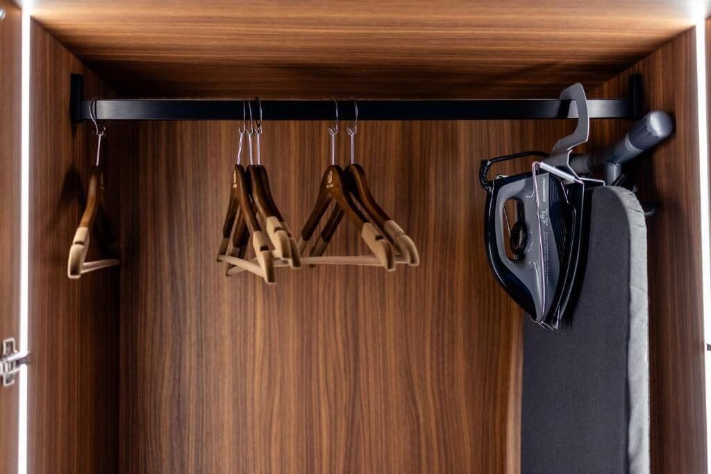 A wooden wardrobe with a black hanger rack and a vacuum cleaner.