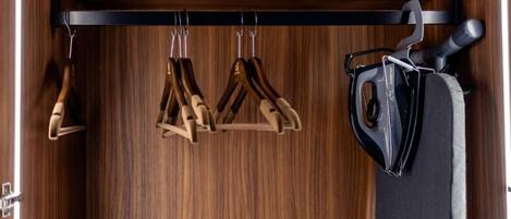 Une armoire en bois avec une tringle à vêtements noire et un aspirateur.
