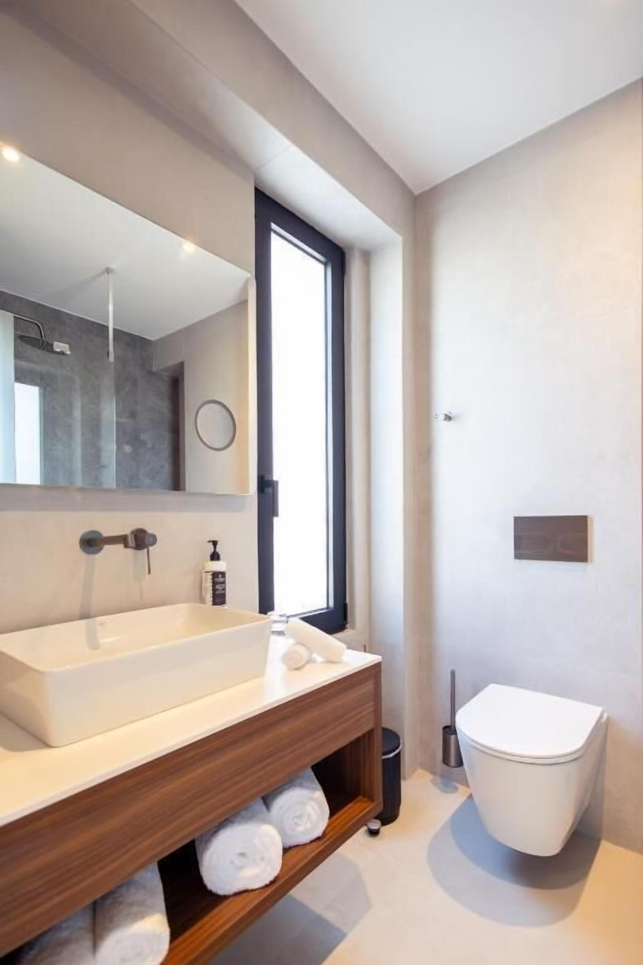 Un baño moderno con un lavamanos grande, un inodoro y una ducha.