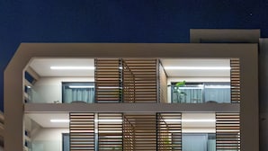 Un hotel de varios pisos con diseño moderno, que presenta balcones con listones de madera, ventanas grandes y un letrero que dice TAYS HOTEL.