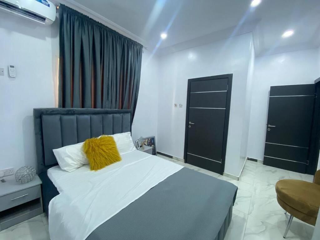 Une chambre d’hôtel avec un lit, une table de chevet, une chaise et deux portes.