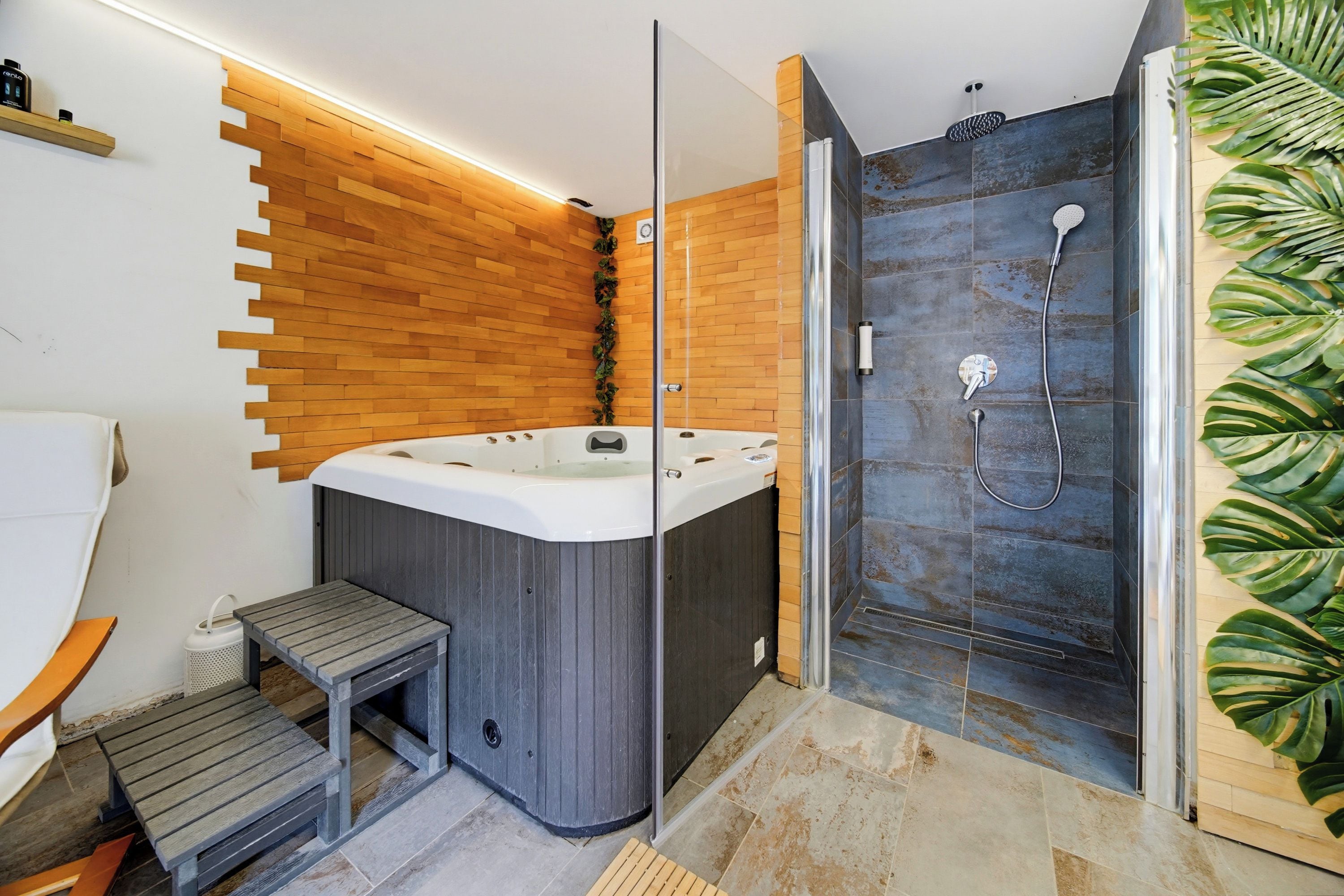 A modern bathroom with a wooden wall, a glass-enclosed shower, and a hot tub.