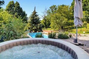 A hot tub surrounded by lush greenery and a swimming pool in the background. - Holiday Home With Pool And Wellness (Sveti Ivan Zelina)