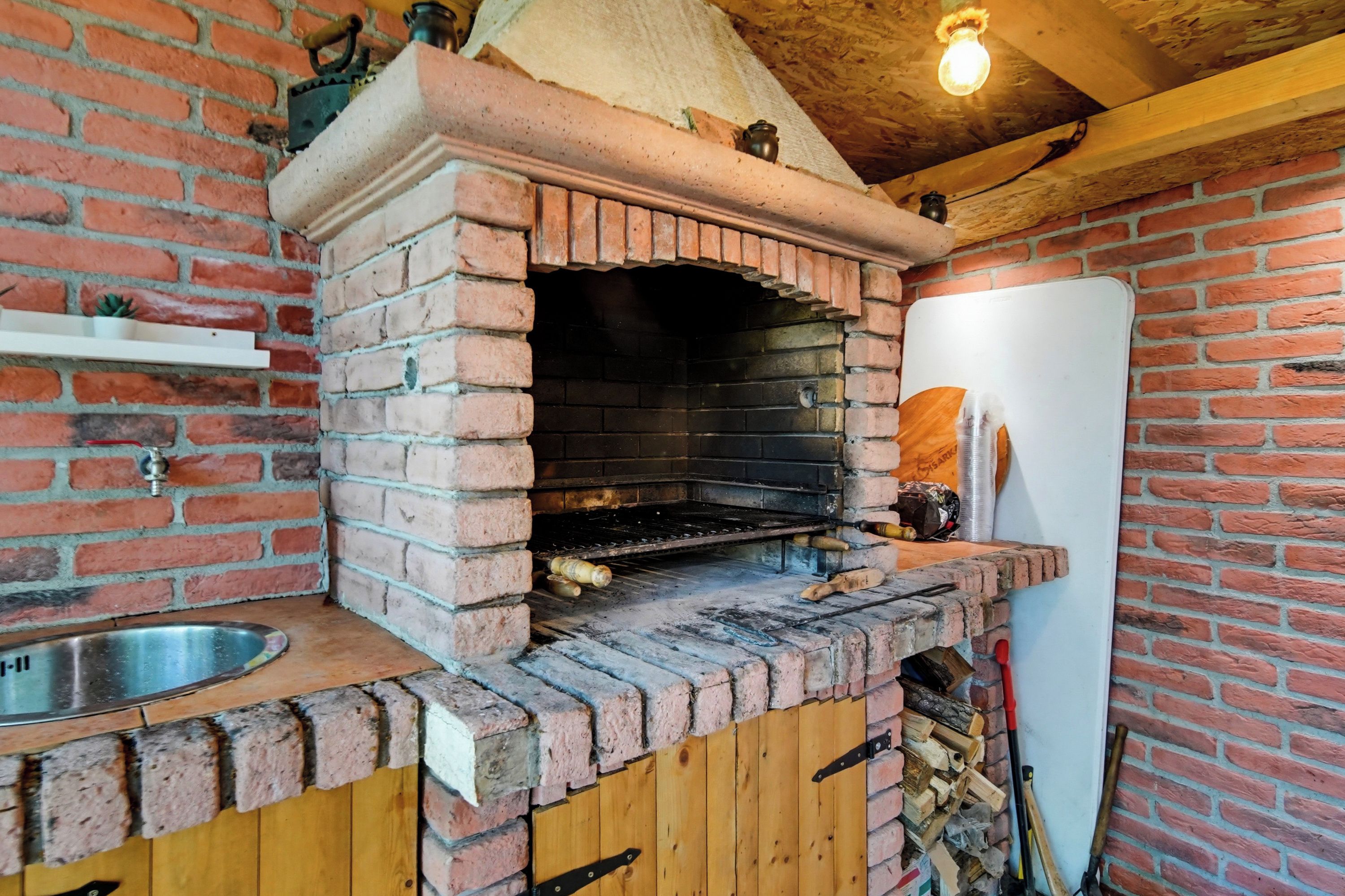 Un four en briques avec un comptoir en bois et un évier, un tableau blanc et un mur en briques.