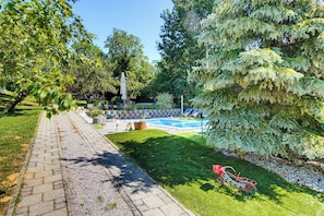 A backyard with a swimming pool, a paved pathway, and a bicycle. - Holiday Home With Pool And Wellness (Sveti Ivan Zelina)