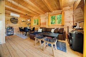 A wooden cabin interior with a dining area, sofa, and a bar with bottles. - Holiday Home With Pool And Wellness (Sveti Ivan Zelina)